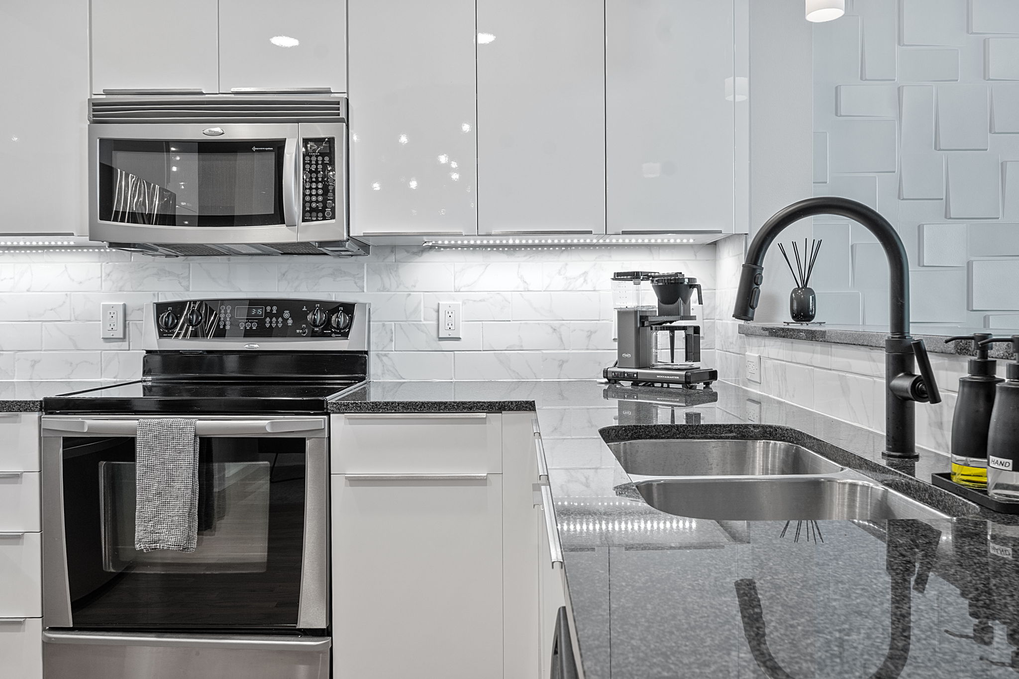 360 Nueces Street, Unit 1007 Austin, TX 78701 - Photo 11 of 40 Kitchen with appliances with stainless steel finishes, white cabinets, dark stone countertops, and backsplash