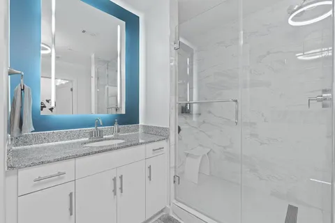 a bathroom with a granite countertop sink a mirror and a shower