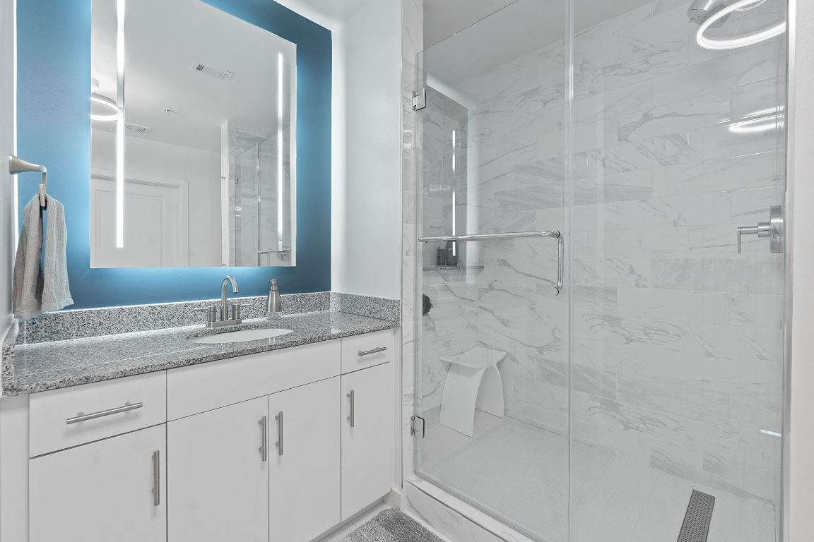 360 Nueces Street, Unit 1007 Austin, TX 78701 - Photo 23 of 40 a bathroom with a granite countertop sink a mirror and shower