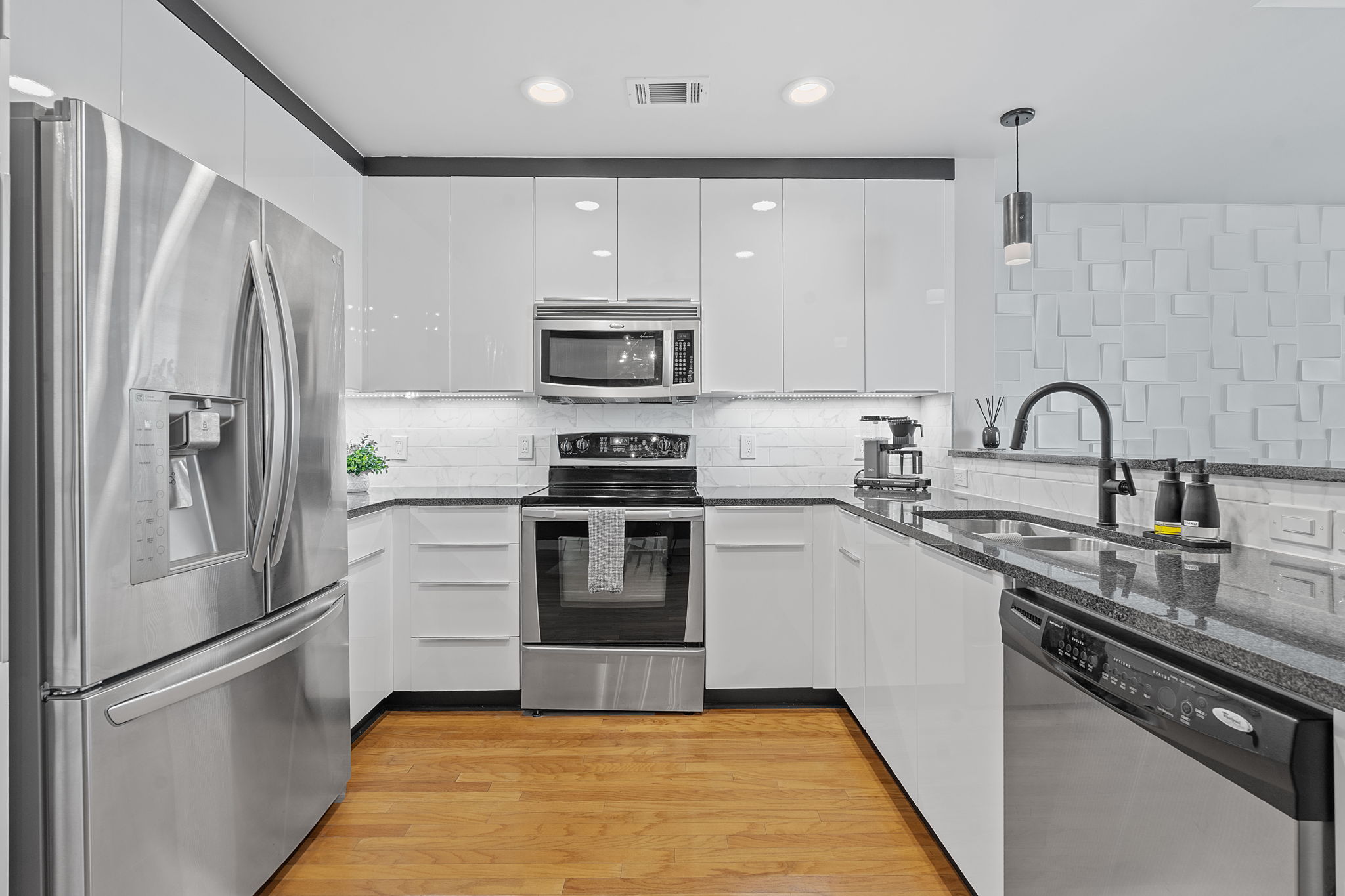 360 Nueces Street, Unit 1007 Austin, TX 78701 - Photo 10 of 40 Kitchen featuring appliances with stainless steel finishes, dark stone counters, tasteful backsplash, hanging light fixtures, and white cabinetry