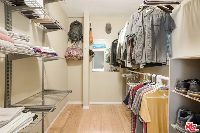 a view of walk in closet with clothes and shoes
