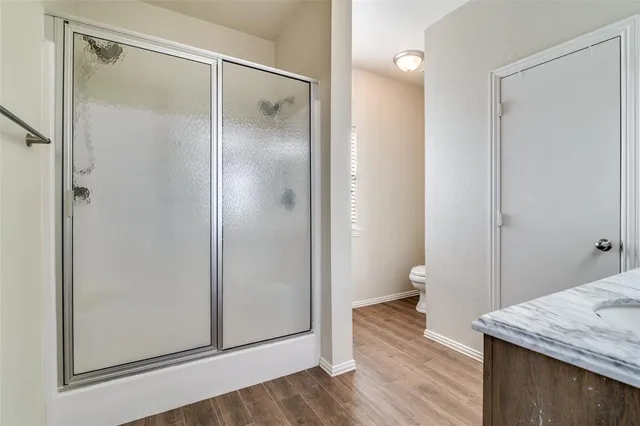 a bathroom with a granite countertop shower a toilet and a sink