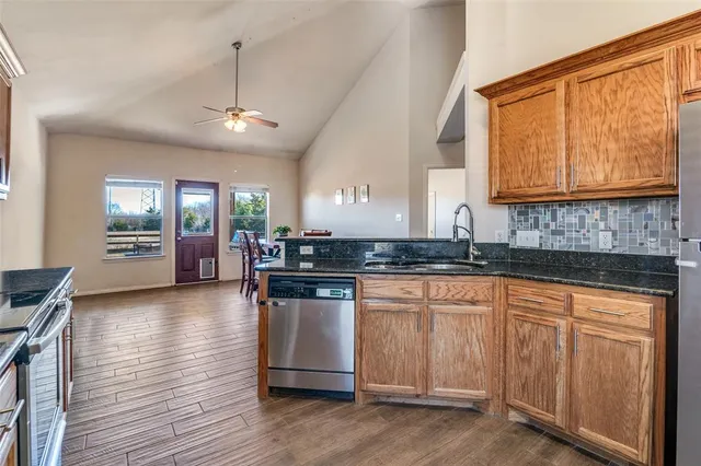 a kitchen with granite countertop a stove a sink dishwasher and a microwave oven with wooden floor