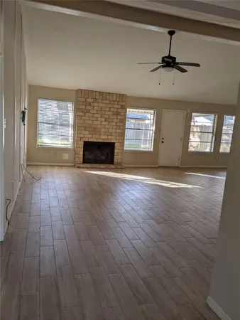 an empty room with windows fireplace and wooden floor
