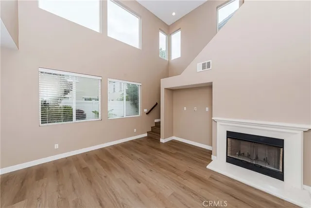 a view of an empty room with wooden floor fireplace and a window