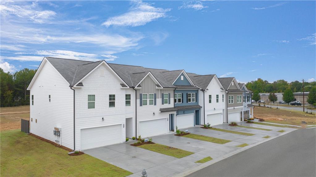a view of a white house with a small yard and large tree