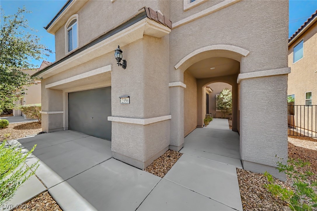 2356 Rue Bienville Way Henderson, NV 89044 - Photo 2 of 20 This charming home offers an inviting exterior with a convenient attached garage and a welcoming arched entryway.