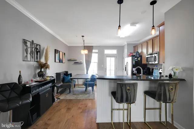 a kitchen with stainless steel appliances granite countertop a stove top oven a sink a dining table and chairs with wooden floor