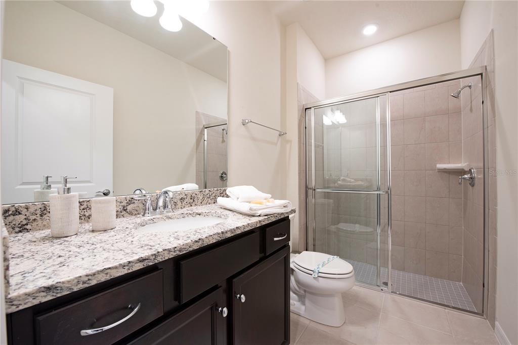 126 Jetty Way Davenport, FL 33897 - Photo 15 of 52 a bathroom with a granite countertop sink toilet a mirror and shower