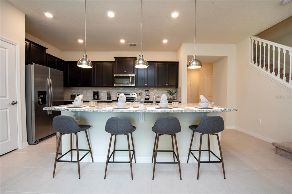 126 Jetty Way Davenport, FL 33897 - Photo 7 of 52 a kitchen with stainless steel appliances kitchen island granite countertop a table chairs and a refrigerator