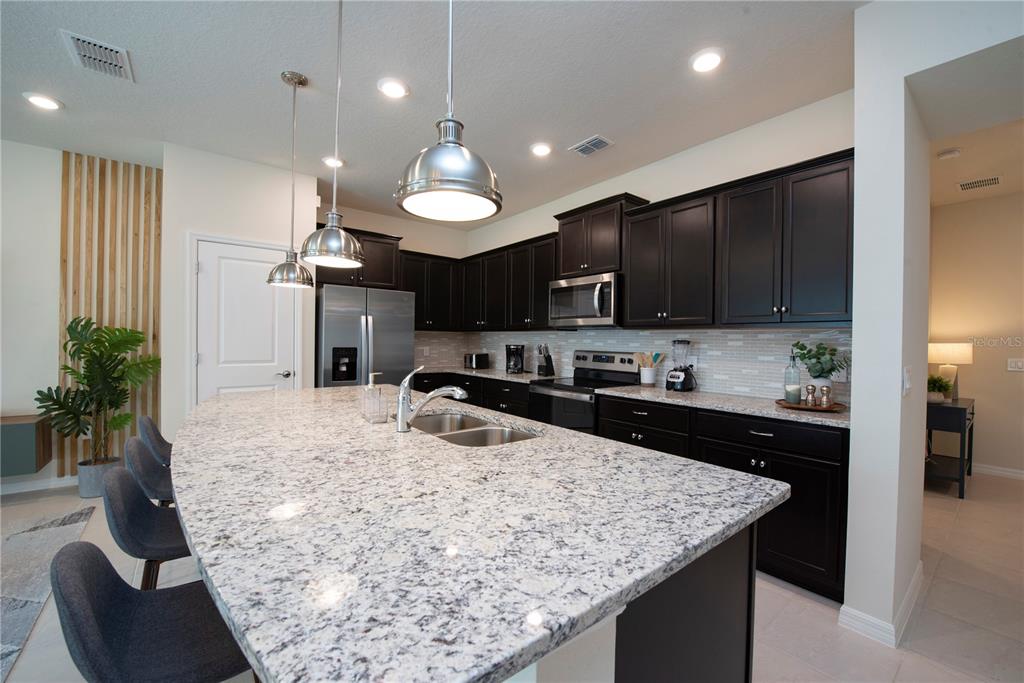 126 Jetty Way Davenport, FL 33897 - Photo 10 of 52 a kitchen with kitchen island granite countertop a sink a stove and refrigerator