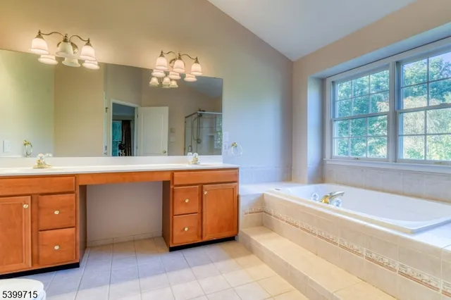 a spacious bathroom with a tub sink and a mirror