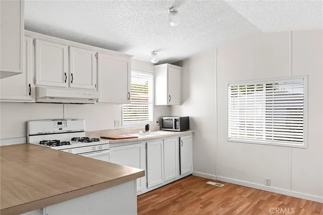 a room with stainless steel appliances granite countertop a sink a stove a refrigerator and cabinets