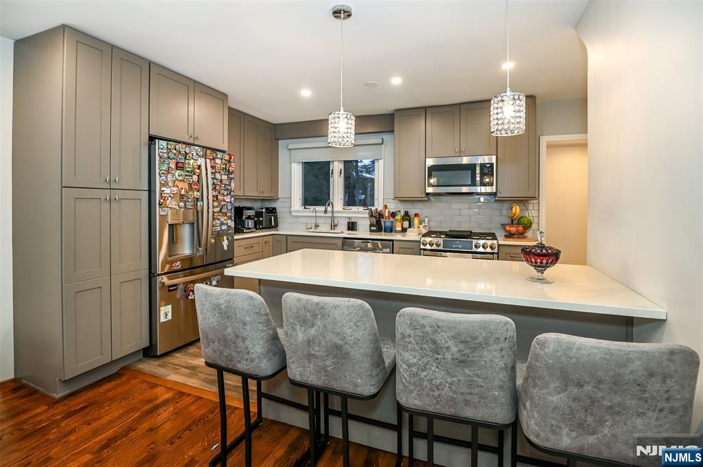 260 Kensington Road River Edge, NJ 07661 - Photo 2 of 22 a kitchen with stainless steel appliances granite countertop a refrigerator a sink a stove a dining table and chairs