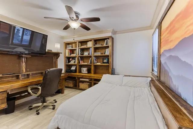 a bedroom with a bed a desk and book shelfs