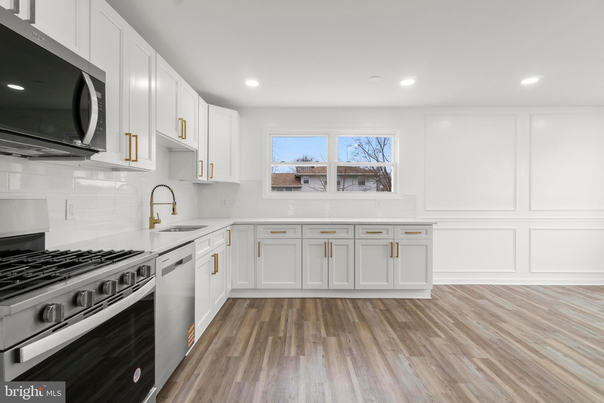 998 Kingston Drive Cherry Hill, NJ 08034 - Photo 19 of 35 a kitchen with stainless steel appliances a stove top oven a sink dishwasher and microwave with wooden floor