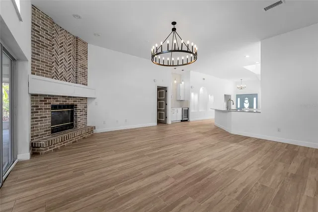 a view of an empty room with wooden floor and fire place