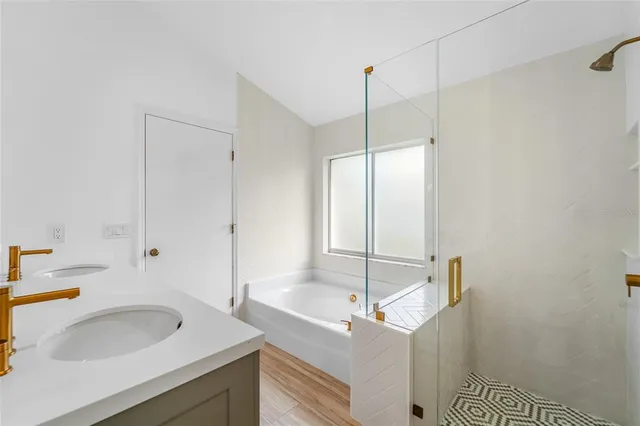 a bathroom with a sink tub vanity and a shower