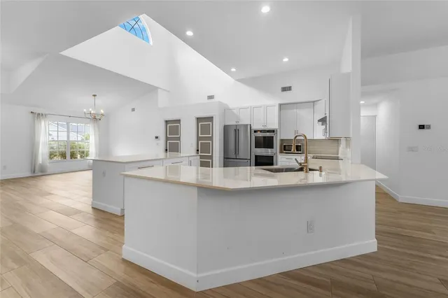 a kitchen with stainless steel appliances granite countertop a sink a stove and a wooden floors
