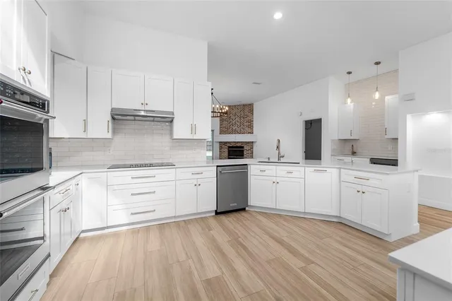 a large kitchen with cabinets wooden floor and stainless steel appliances