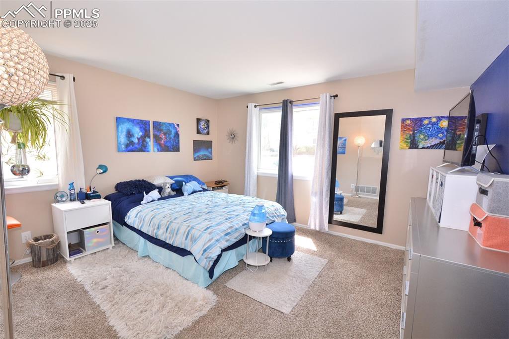 846 Tenderfoot Hill Road, Unit 104 Colorado Springs, CO 80906 - Photo 10 of 13 a bedroom with a bed and a large mirror next to a window