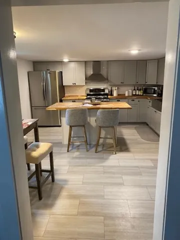 a living room with stainless steel appliances kitchen island granite countertop a sink and cabinets