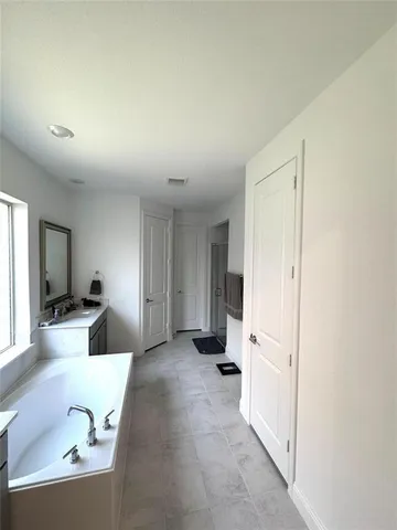 a spacious bathroom with a tub sink and mirror