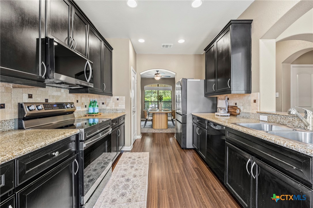 3306 Castleton Drive Killeen, TX 76542 - Photo 11 of 39 a kitchen with stainless steel appliances granite countertop a stove top oven a sink dishwasher a refrigerator and cabinets with wooden floor