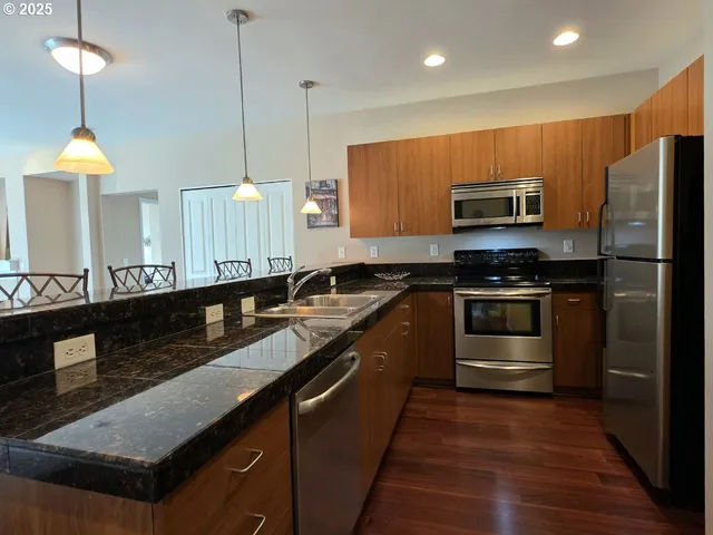 a kitchen with stainless steel appliances granite countertop a sink a stove and a wooden floors