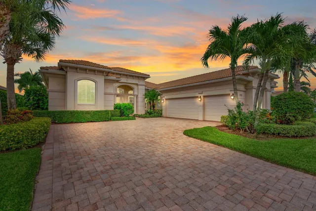 a front view of a house with a garden and palm trees