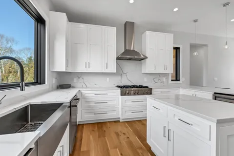 a kitchen with stainless steel appliances a stove a sink and white cabinets