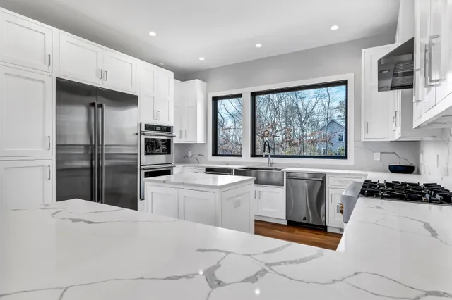 a kitchen with stainless steel appliances granite countertop a stove top oven a sink a dining table and chairs with wooden floor