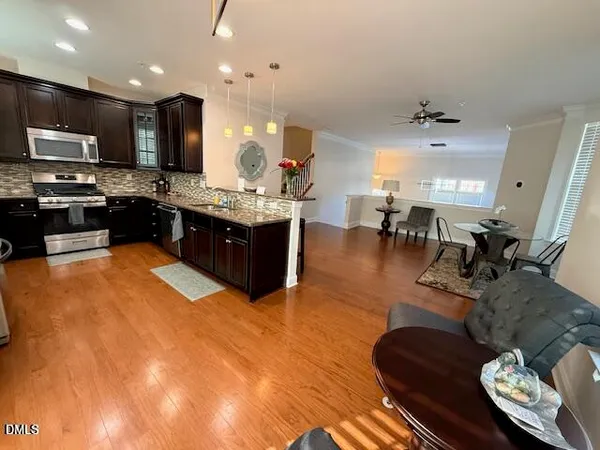 a kitchen with stainless steel appliances kitchen island granite countertop a refrigerator a stove a sink and a dining table with wooden floor