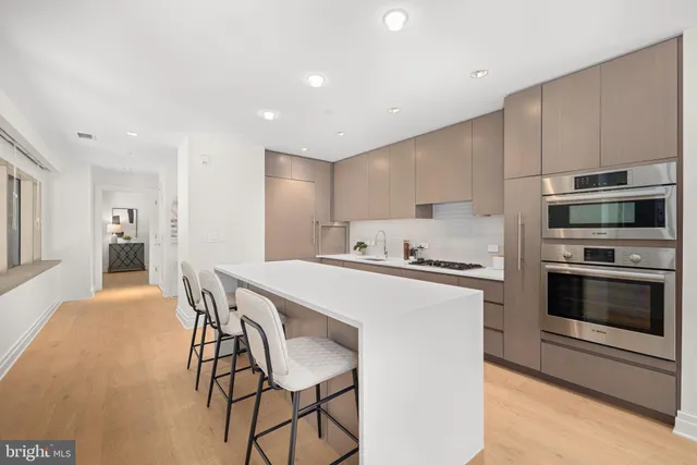 a kitchen with stainless steel appliances a stove a microwave a sink and white cabinets