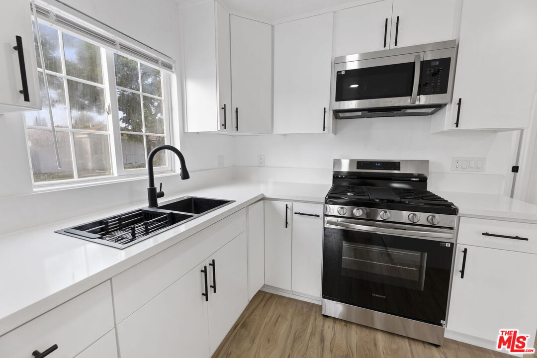 6833 Crafton Avenue Bell, CA 90201 - Photo 14 of 33 a kitchen with stainless steel appliances a stove a microwave and cabinets