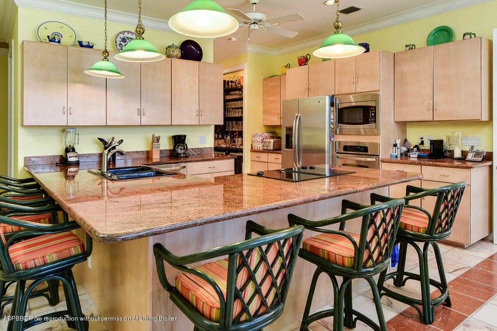 1680 Lands End Road Manalapan, FL 33462 - Photo 11 of 15 a kitchen with stainless steel appliances granite countertop a table chairs in it and wooden floors