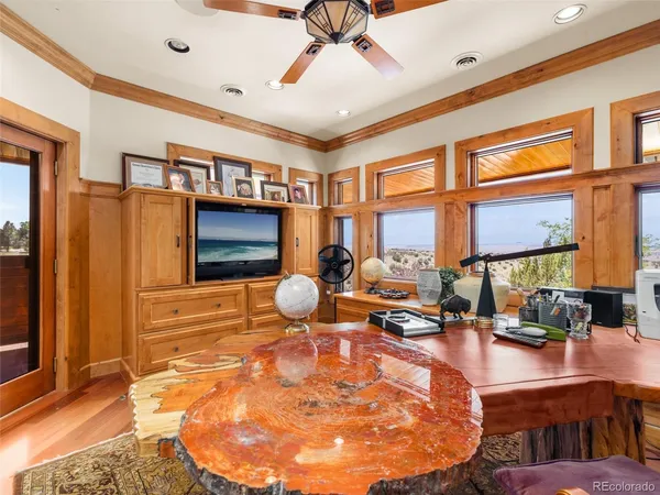 a room with lots of tables a large window and potted plants