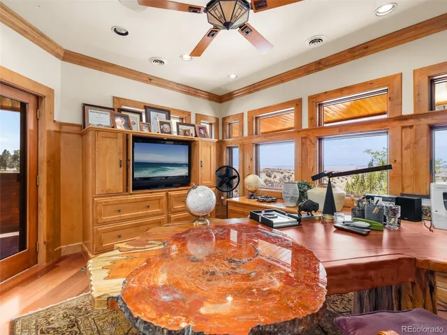 a room with lots of tables a large window and potted plants