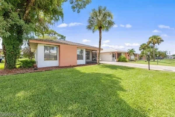 a front view of a house with yard and tree