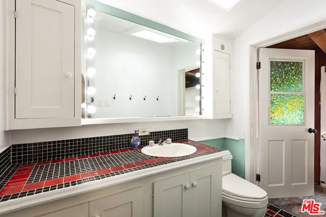 a bathroom with a sink a toilet a mirror and a window