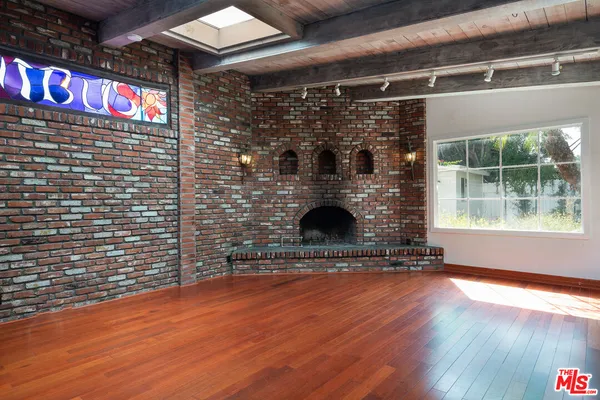a view of an empty room with wooden floor and a fireplace