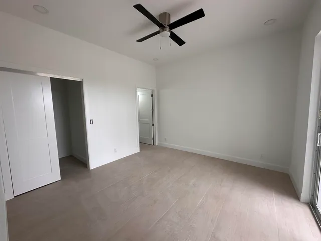 an empty room with a ceiling fan and window
