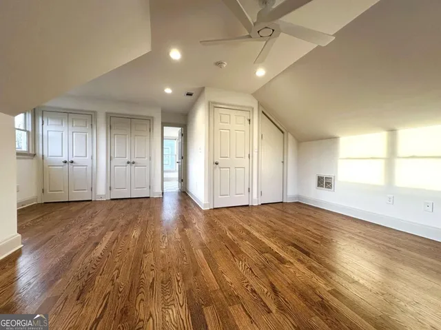 a view of empty room with wooden floor and fan