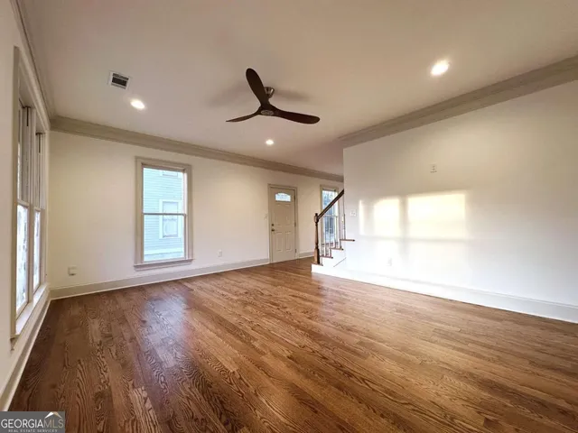 an empty room with wooden floor and windows