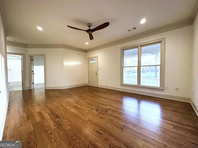 a view of an empty room with wooden floor and a window
