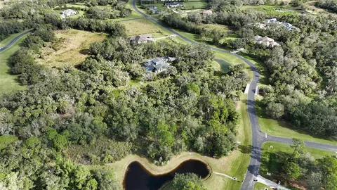 an aerial view of residential house with outdoor space and trees all around