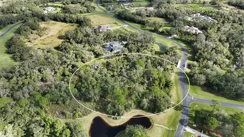 an aerial view of residential house with outdoor space and trees all around
