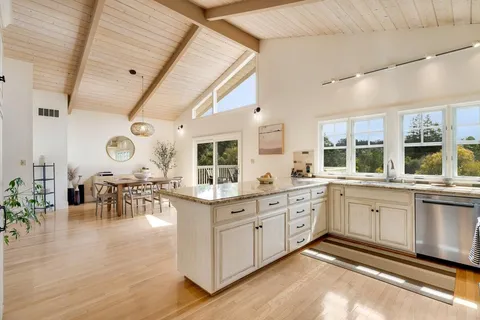 a large white kitchen with lots of counter space and chandelier