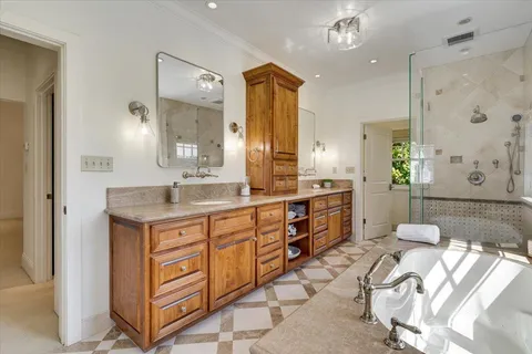 a spacious bathroom with double vanity sinks a large mirror and a shower