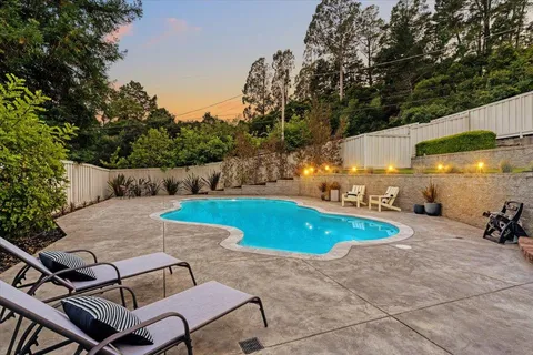 a view of a swimming pool with lawn chairs under an umbrella